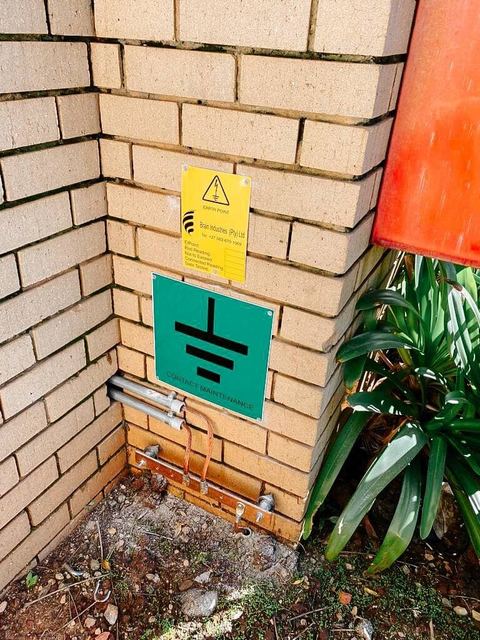 Earth mat warning sign mounted on a brick wall next to MV switchgear