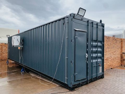 Grey steel container unit with external floodlight on site